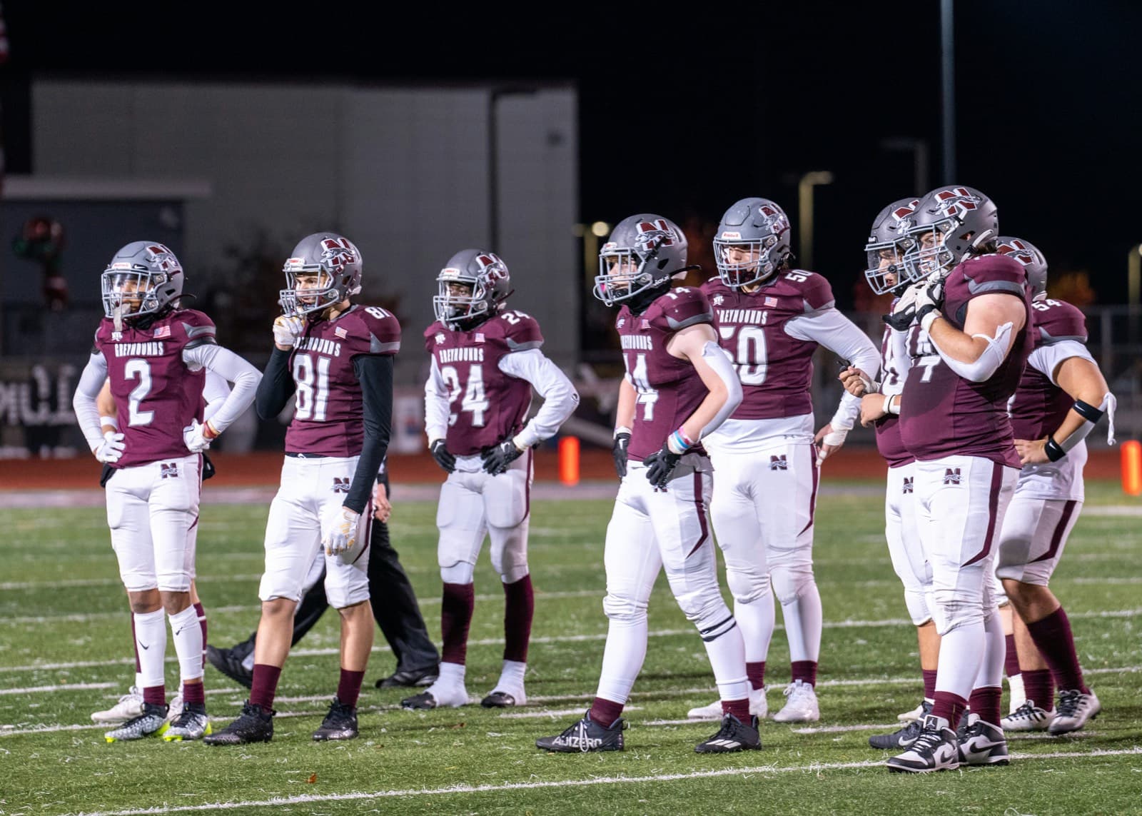 A youth football team standing together on the field under the lights